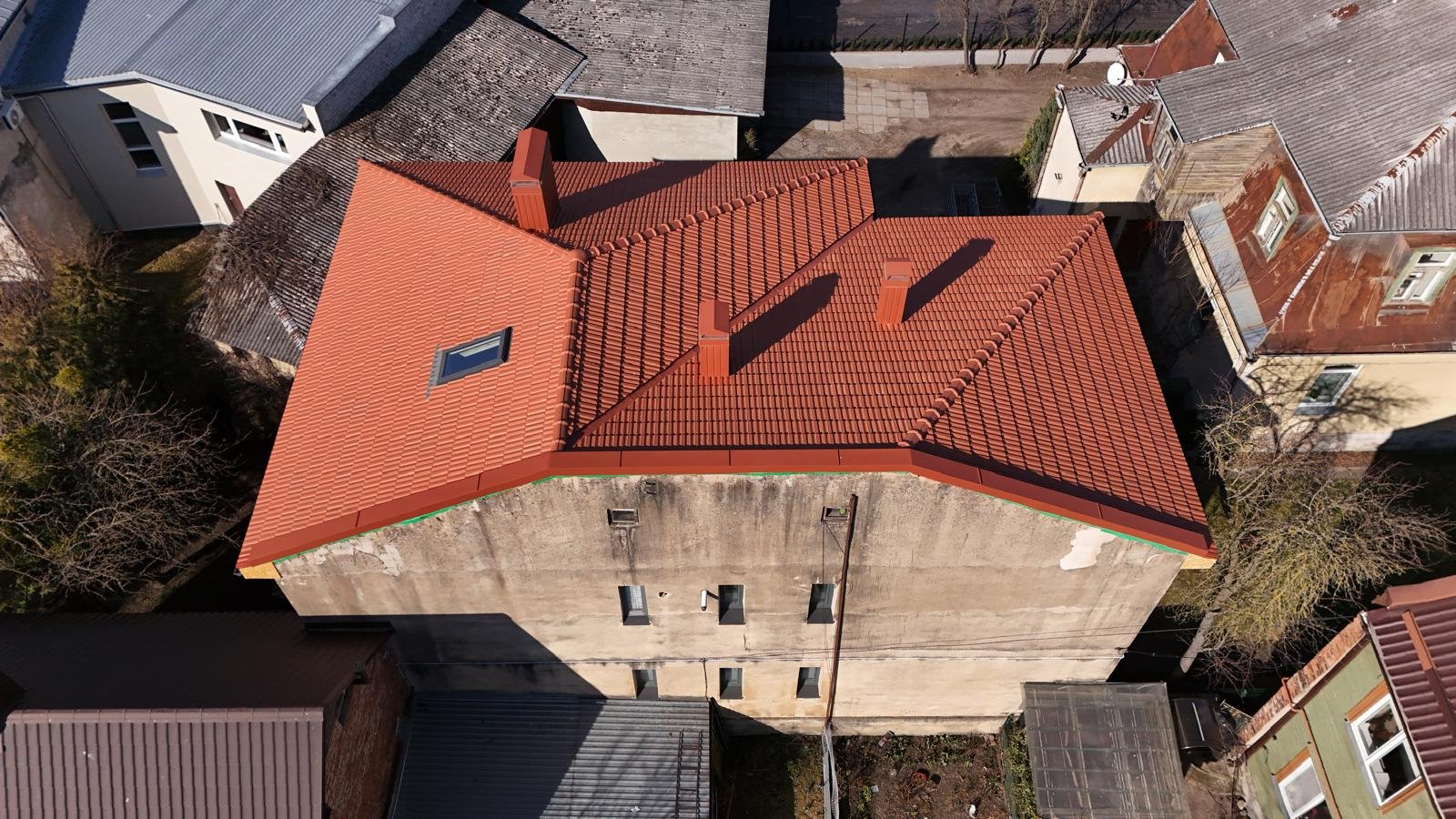 Iš oro matomas renovuotas sudėtingos formos terakotos spalvos čerpinis stogas